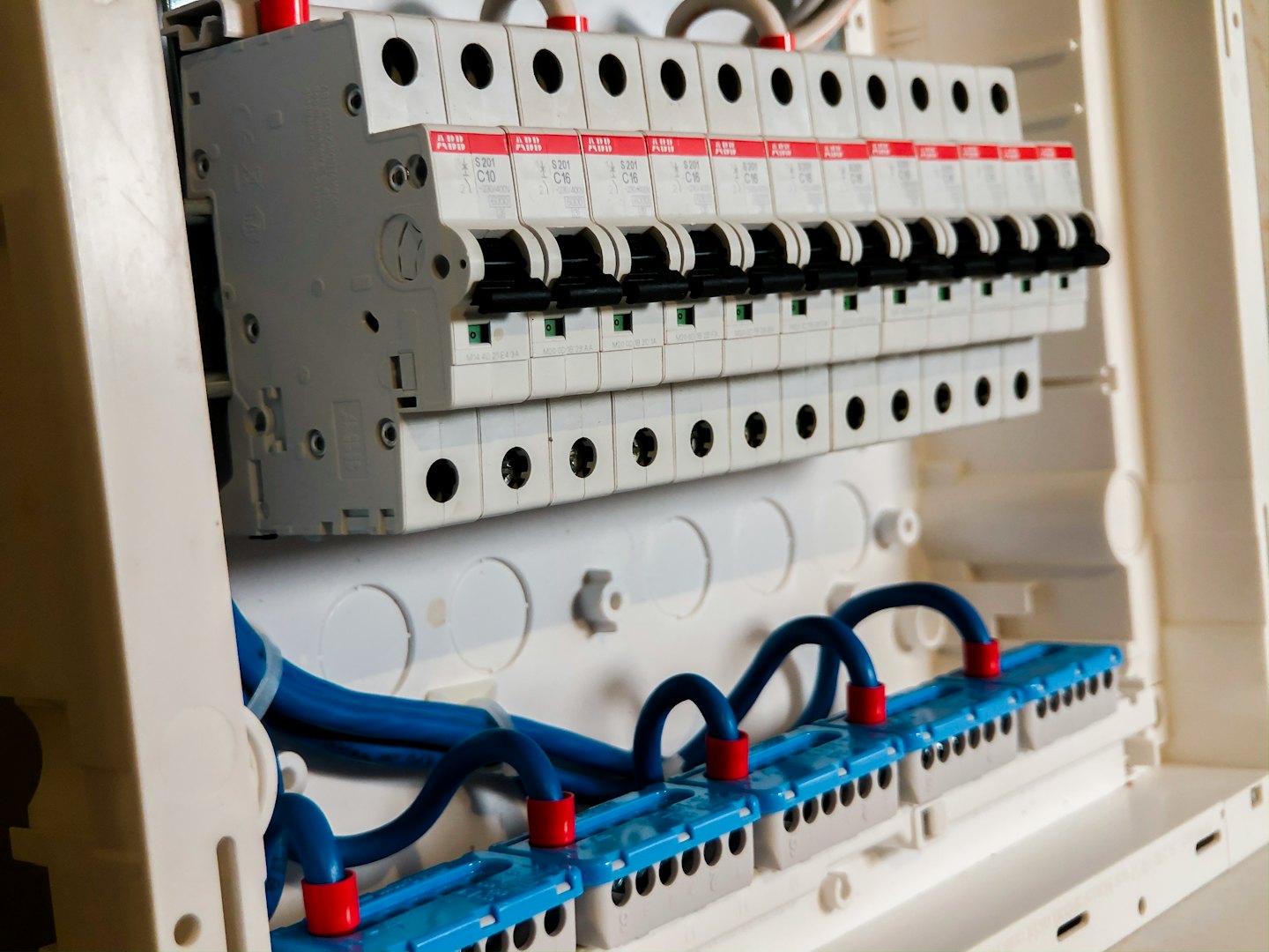 Rozdzielnica elektryczna z rzędami wyłączników i niebieskimi przewodami.