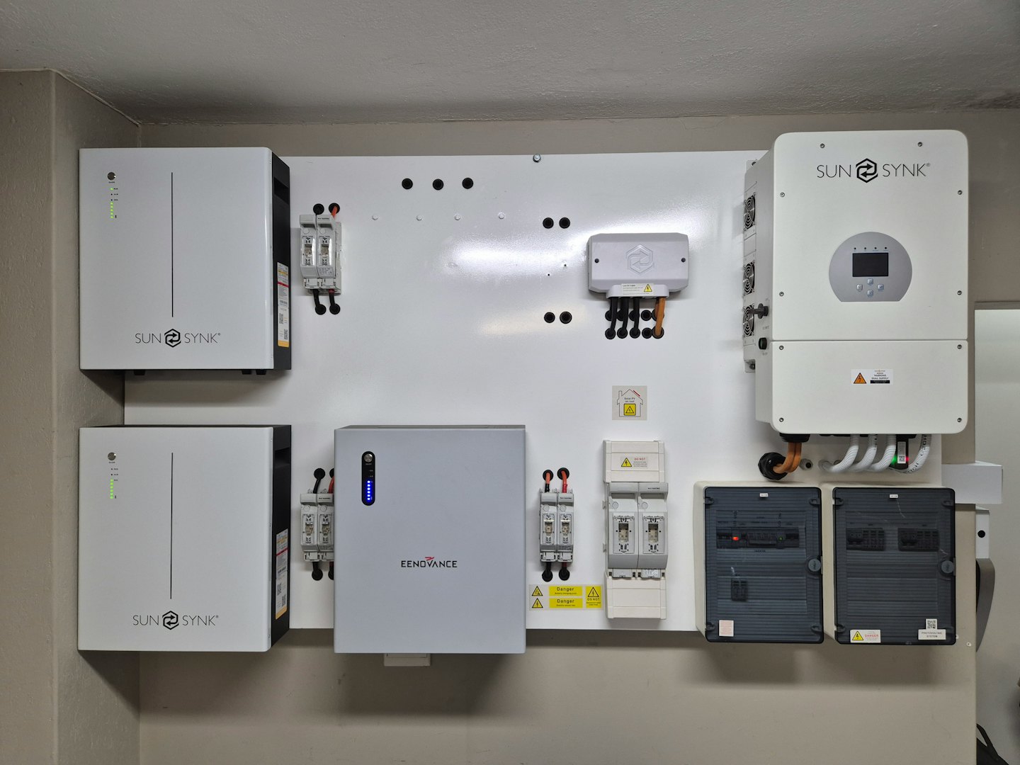 Domowy system energetyczny z akumulatorami i falownikami na białej ścianie.